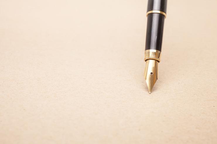Füllfederhalter mit goldener Spitze auf braunem Papier.